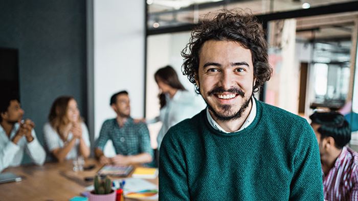 Glad man i grön tröja i ett mötesrum