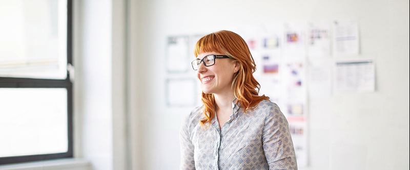 Kvinna i ljus skjorta som ler och tittar på en kollega