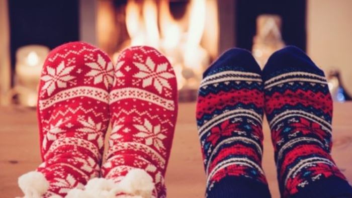 Fötter med julsockor framför brasa