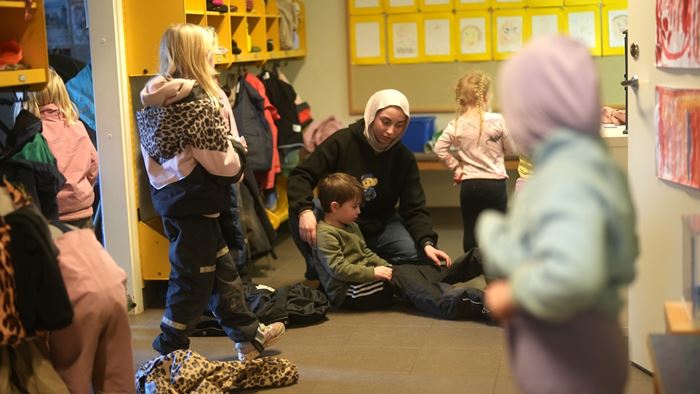 Förskolepersonal hjälper barn med påklädning