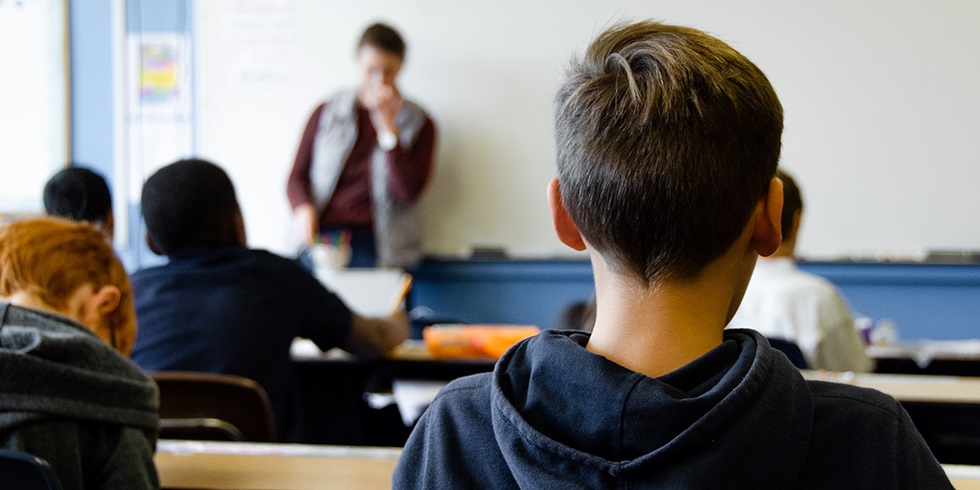 pojke i blå hoodie och lärare i klassrum