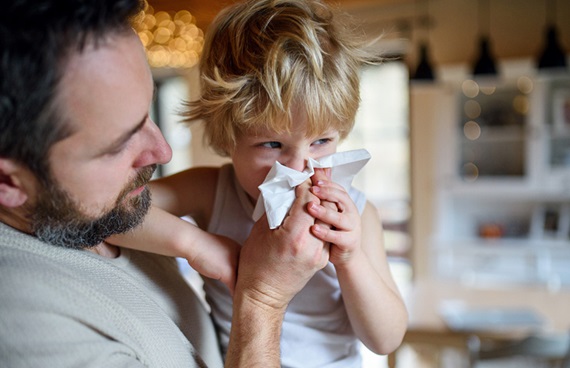 En pappa bär sitt sjuka barn på armen.
